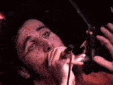 a close up of a man singing into a microphone with blood on his face