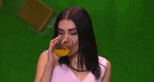 a woman is drinking a glass of orange juice .