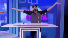 a man is standing at a podium with his arms outstretched and a microphone in front of him .