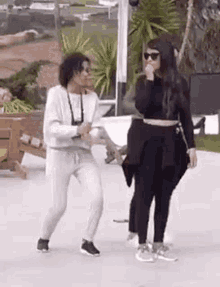 two women are standing next to each other on a sidewalk dancing .