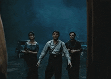 a group of people are standing in a dark room with a lantern .