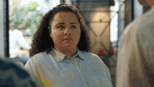 a woman with curly hair wearing a tie dye shirt is talking to a man .
