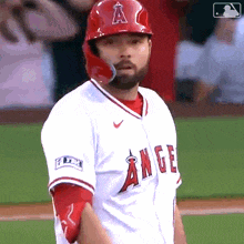 a baseball player for the angels wears a red helmet and white jersey