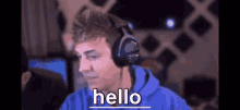 a man wearing headphones is sitting in front of a computer and says hello .