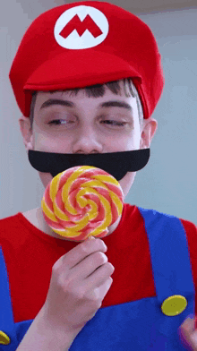 a man dressed as mario is holding a lollipop in his mouth