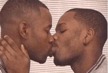 two men are kissing each other on the cheek .