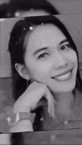a black and white photo of a woman with her hand on her chin