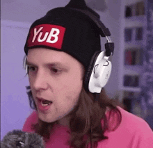 a man wearing a beanie and headphones is making a funny face while talking into a microphone .
