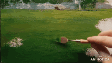 a person is painting a green field with a brush and the words made in animotica on the bottom