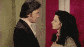 a man in a suit and a woman in a dress are looking at each other