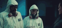 two men wearing protective suits and goggles are standing next to each other and talking to each other .