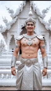 a shirtless man in a silver costume is standing in front of a white building
