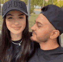 a man is kissing a woman on the cheek while she is wearing a hat .