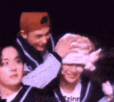 a group of people are standing next to each other and one of them is holding a stuffed animal in his hands .