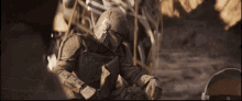 a man wearing a helmet and armor is sitting in the dirt