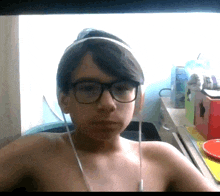 a shirtless boy wearing glasses and headphones looks at the camera