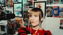 a woman is holding a pair of scissors in front of a wall full of action figures including one that says eminem