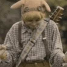 a person wearing a pig mask is playing a guitar .