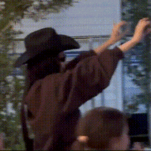 a person wearing a black hat is standing in front of a window