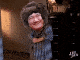 a cartoon of a woman wearing a striped dress and a hat is standing in front of a dresser .