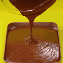 chocolate is being poured into a square pan