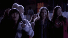 a group of women are standing next to each other in a dark room at night .