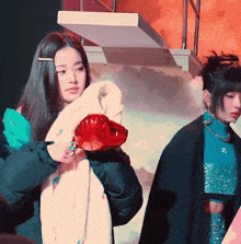 a woman in a white fur coat is holding a red object