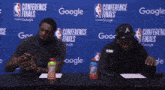 two men sit at a conference finals table