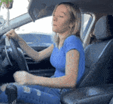 a woman in a blue shirt is sitting in a car with her eyes closed
