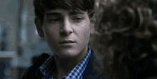 a close up of a young man 's face with a woman behind him .