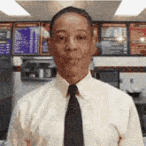 a man in a white shirt and black tie is standing in front of a menu in a restaurant .