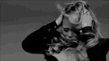 a black and white photo of a woman holding her hair in a ponytail .