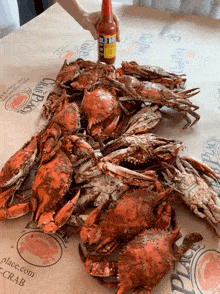 a bottle of hot sauce is being poured over crabs