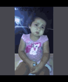 a little girl in a pink shirt with a cat on it