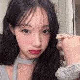 a girl with long black hair is holding a lizard