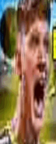 a close up of a man 's face with his mouth open and a cell phone in the background .