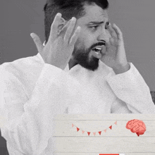 a man with a beard covering his face with his hands