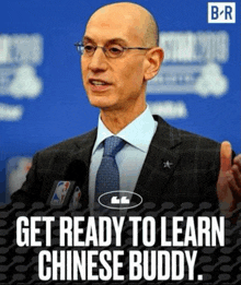 a bald man in a suit and tie is talking into a microphone with the words get ready to learn chinese buddy