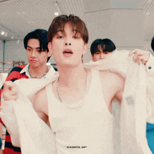 a man in a white tank top is being photographed by khunpol gif *