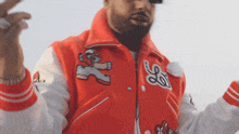 a man wearing a red and white varsity jacket with the letter s on the sleeve