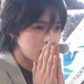 a close up of a person covering their mouth with their hands
