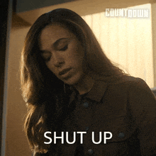 a woman in a brown jacket says shut up in front of a sign that says countdown