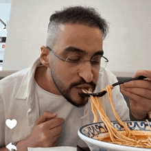 a man wearing glasses is eating noodles with a spoon