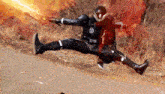 a man in a superhero costume is jumping in the air with a flamethrower .