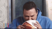 a man in a blue hoodie is eating a bag of kfc nuggets