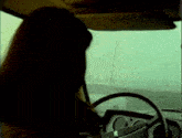 a woman is driving a car with the peugeot logo on the steering wheel