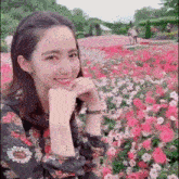 a young woman is sitting in front of a field of pink flowers .