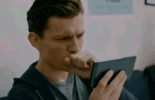 a man is sitting on a couch looking at a tablet .