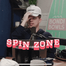 a man sitting in front of a microphone with the words spin zone above him