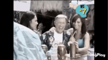 a man and two women are sitting at a table drinking cocktails .